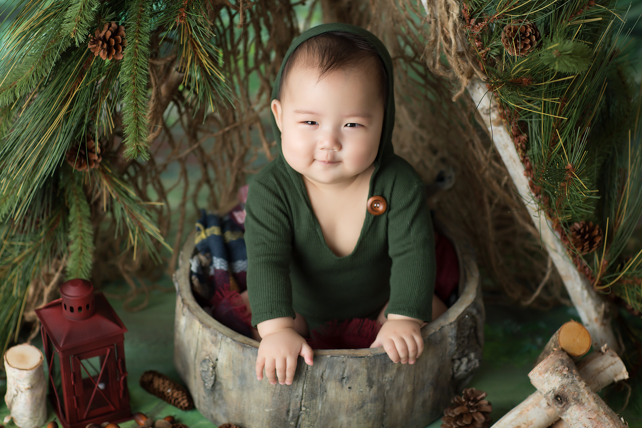 Baby in green sweater in wooden bowl