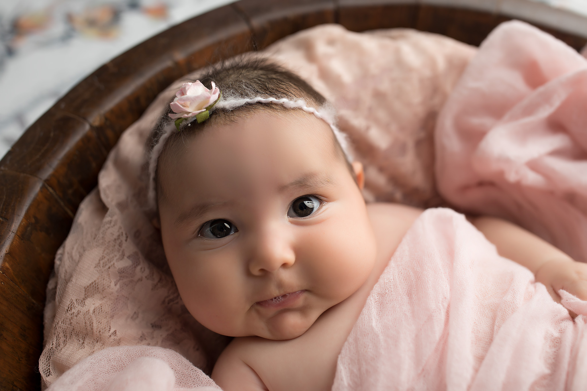 Older newborn girl wrapped in pink with her eyes open. But is baby too old for newborn photos? Nope!
