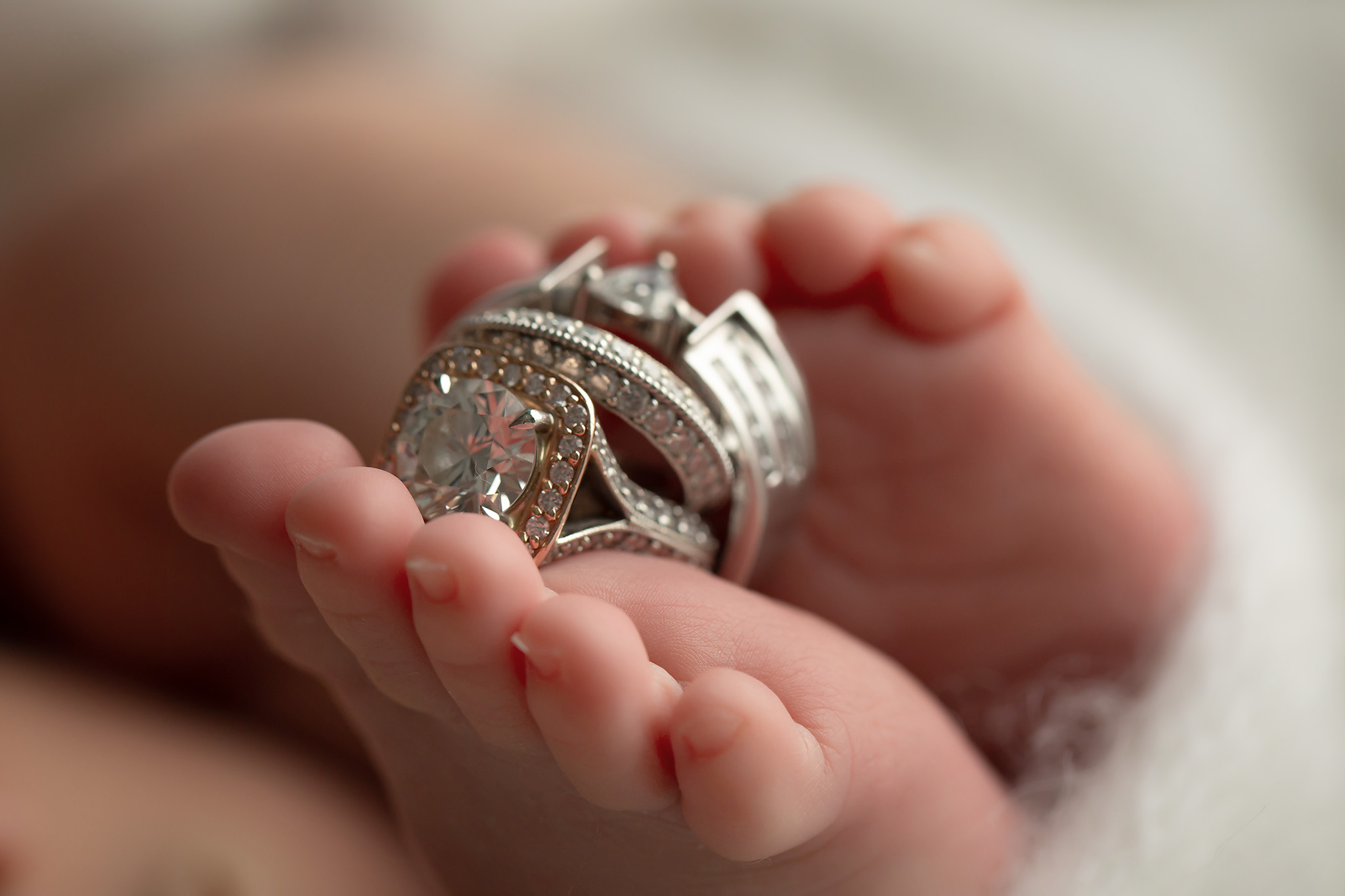 Newborn toes holding parents' wedding rings.