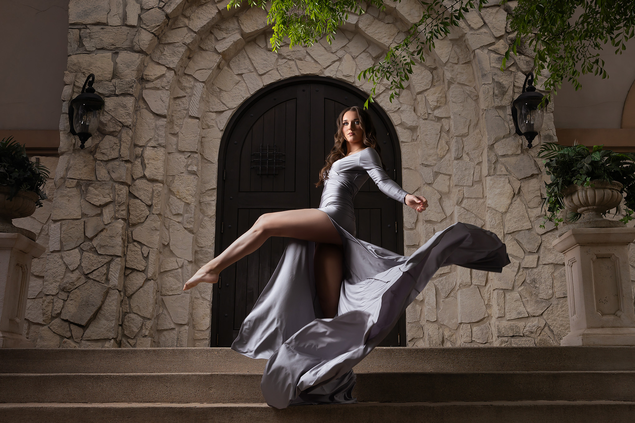 Dramatic senior photo of a girl in a long silver gown and flowing fabric
