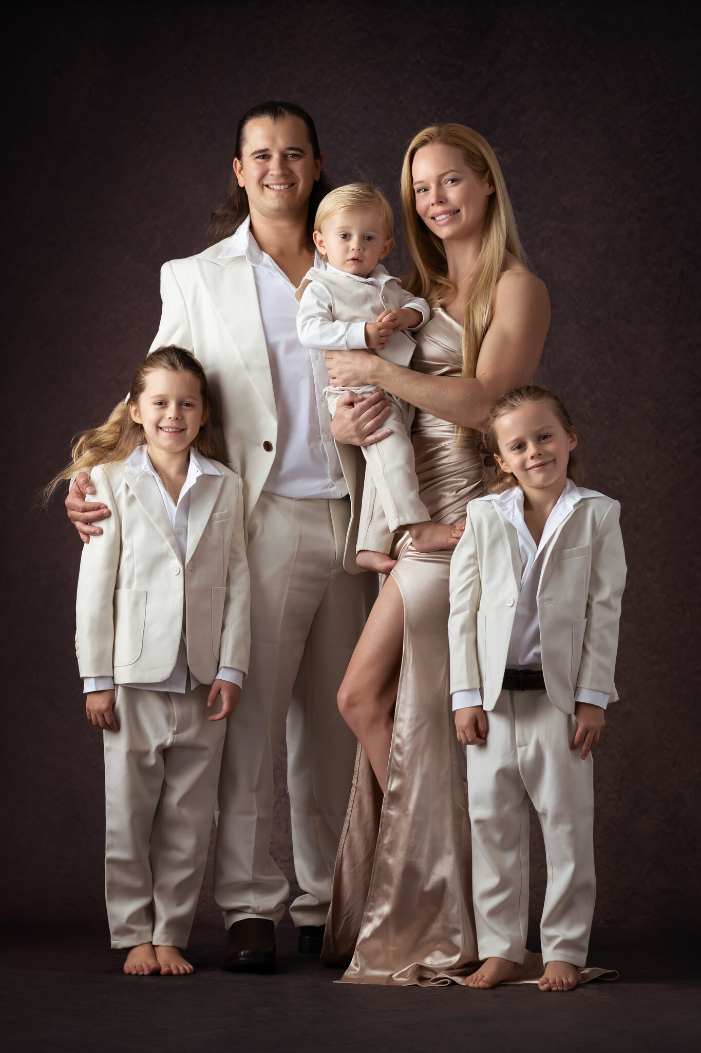 Luxury family photo with the boys all in tan and white suits and mom in a luxurious satin gown from a High End Photographer in Dallas