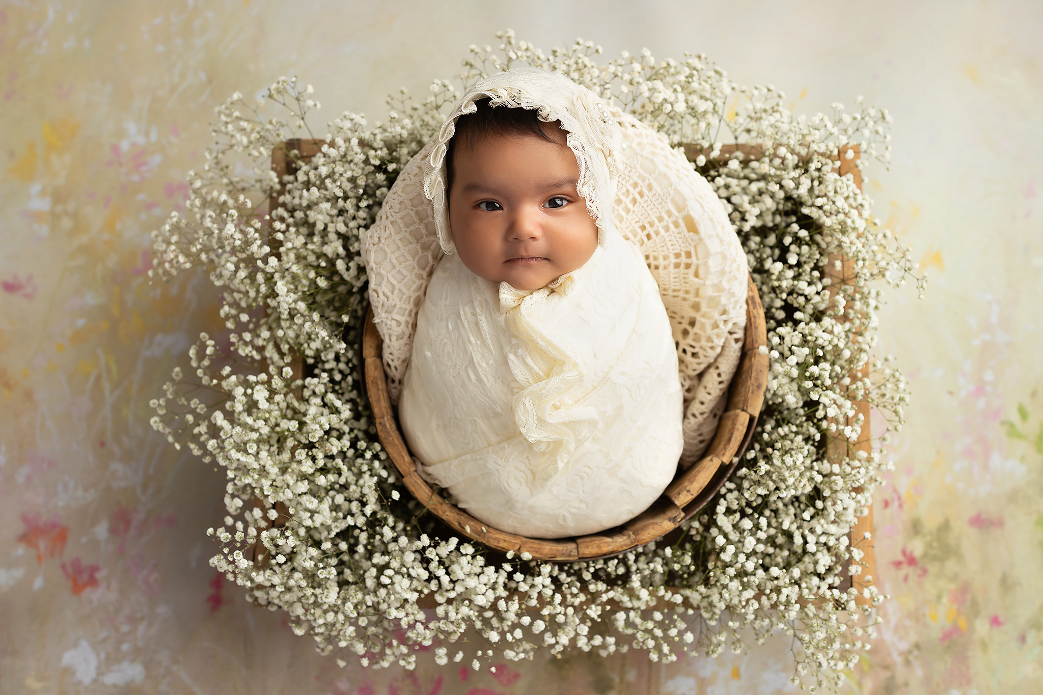 Newborn girl swaddled and surrounded by baby's breath for a cute Baby registry guide for Dallas parents
