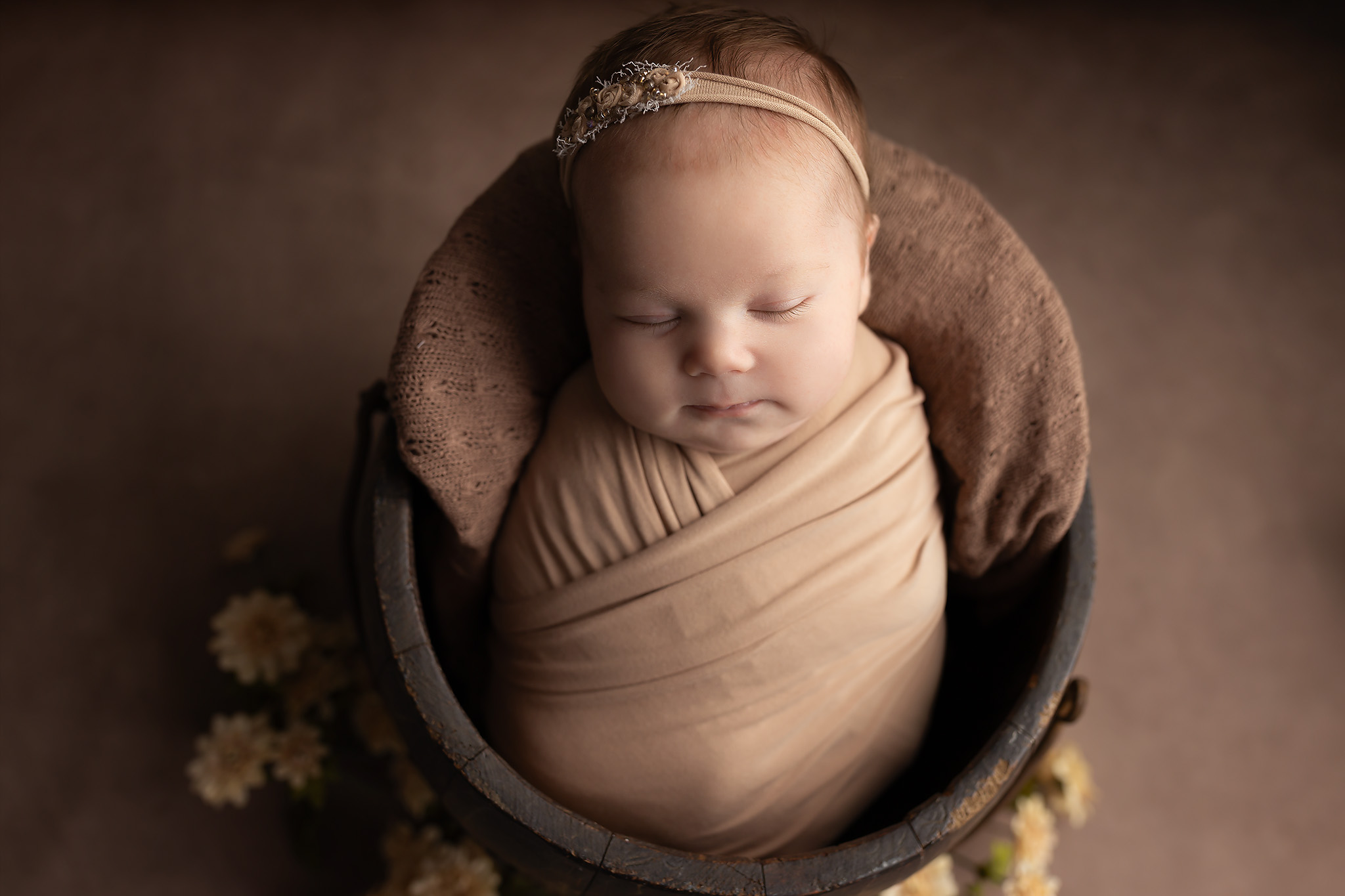 Baby wrapped and sleeping in a bucket.