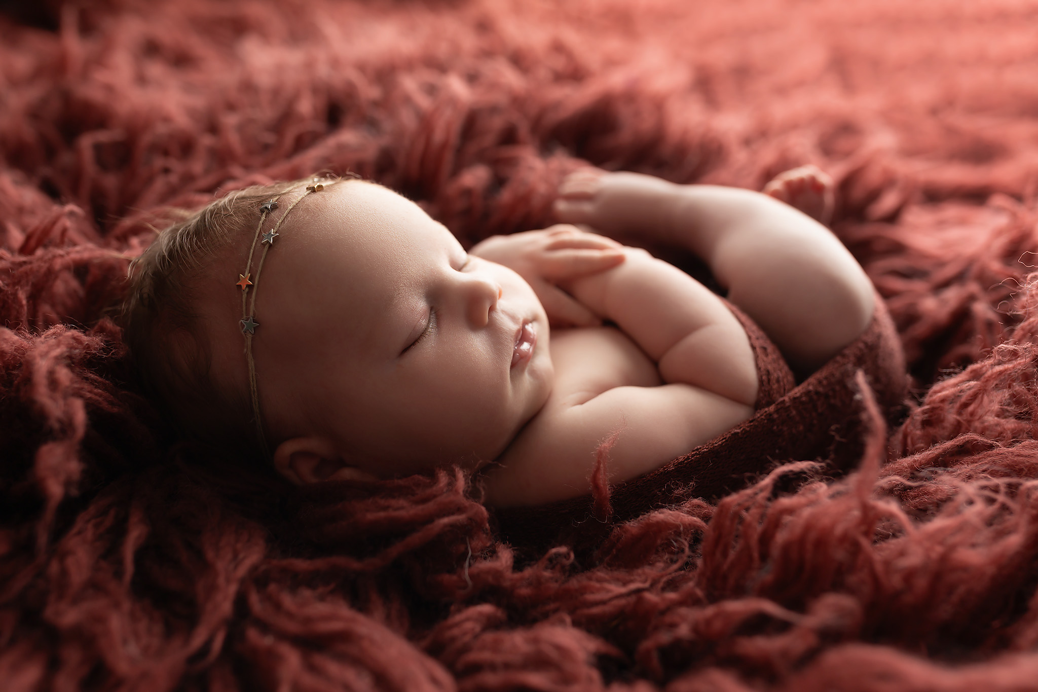 Baby resting in red fluff.