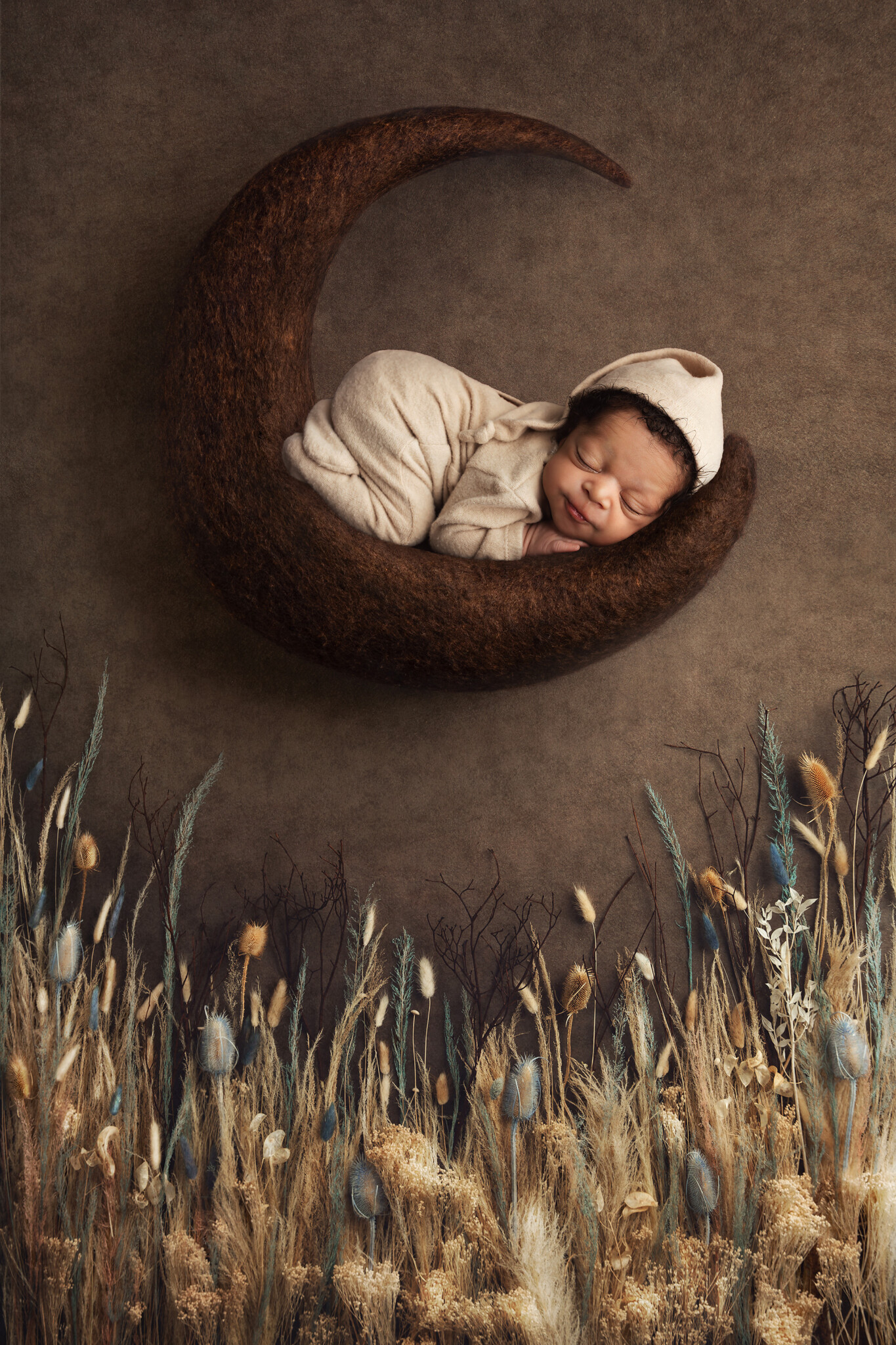Baby resting on brown moon above a field of wheat.