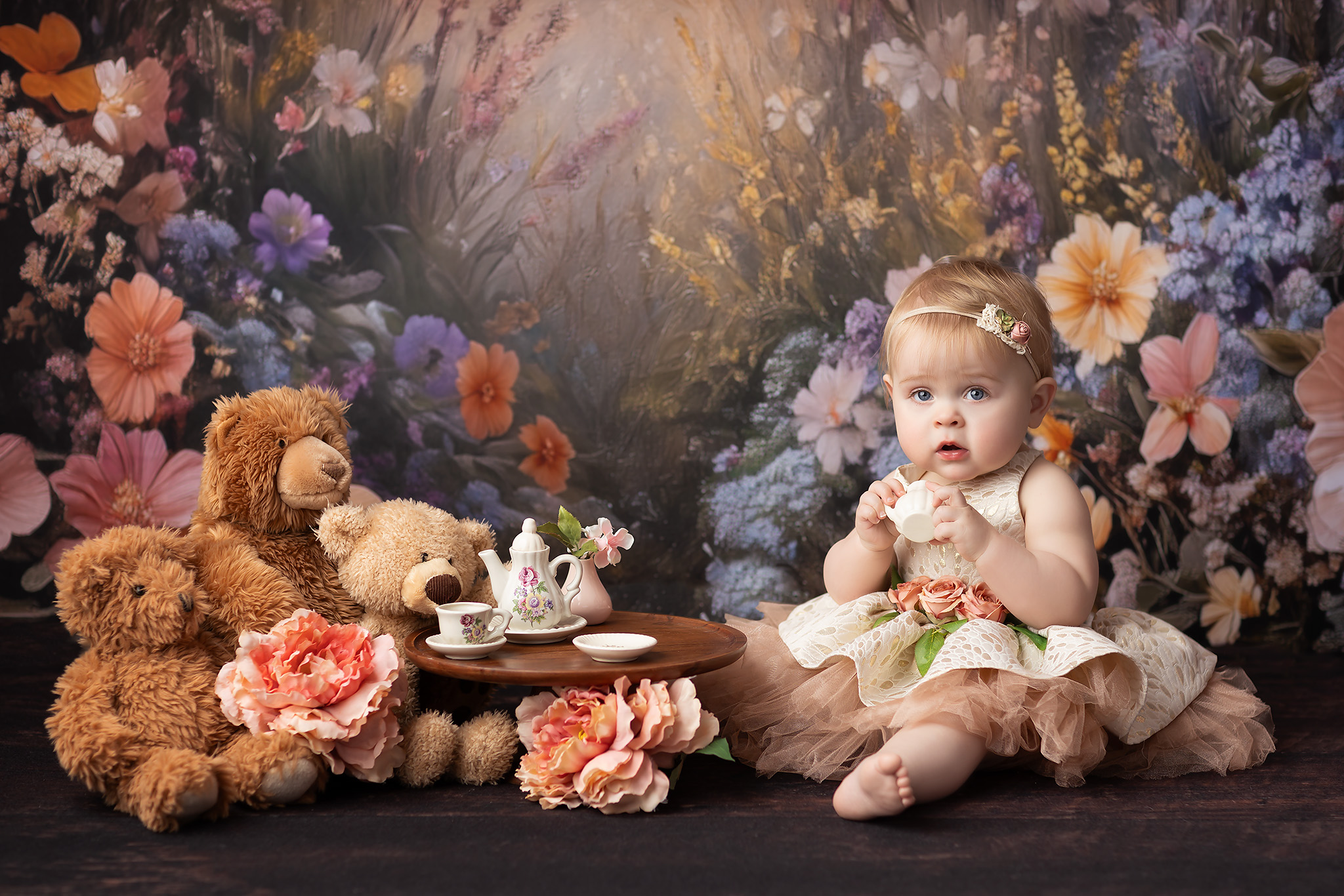 One year old girl playing with a tea set in a pink dress.