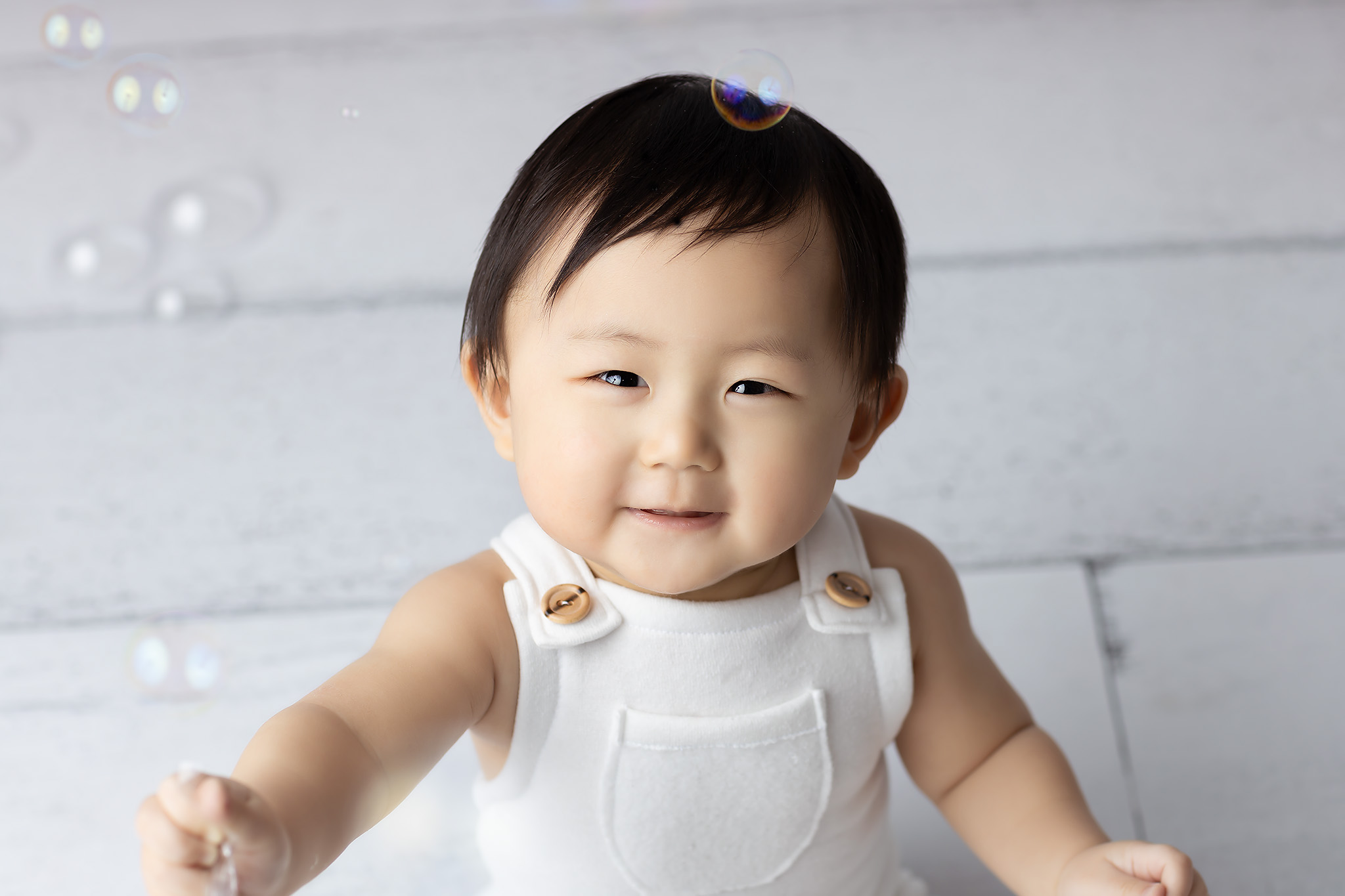 One year old boy smiling playing with bubbles. Your little one can smile at indoor play places in Dallas.