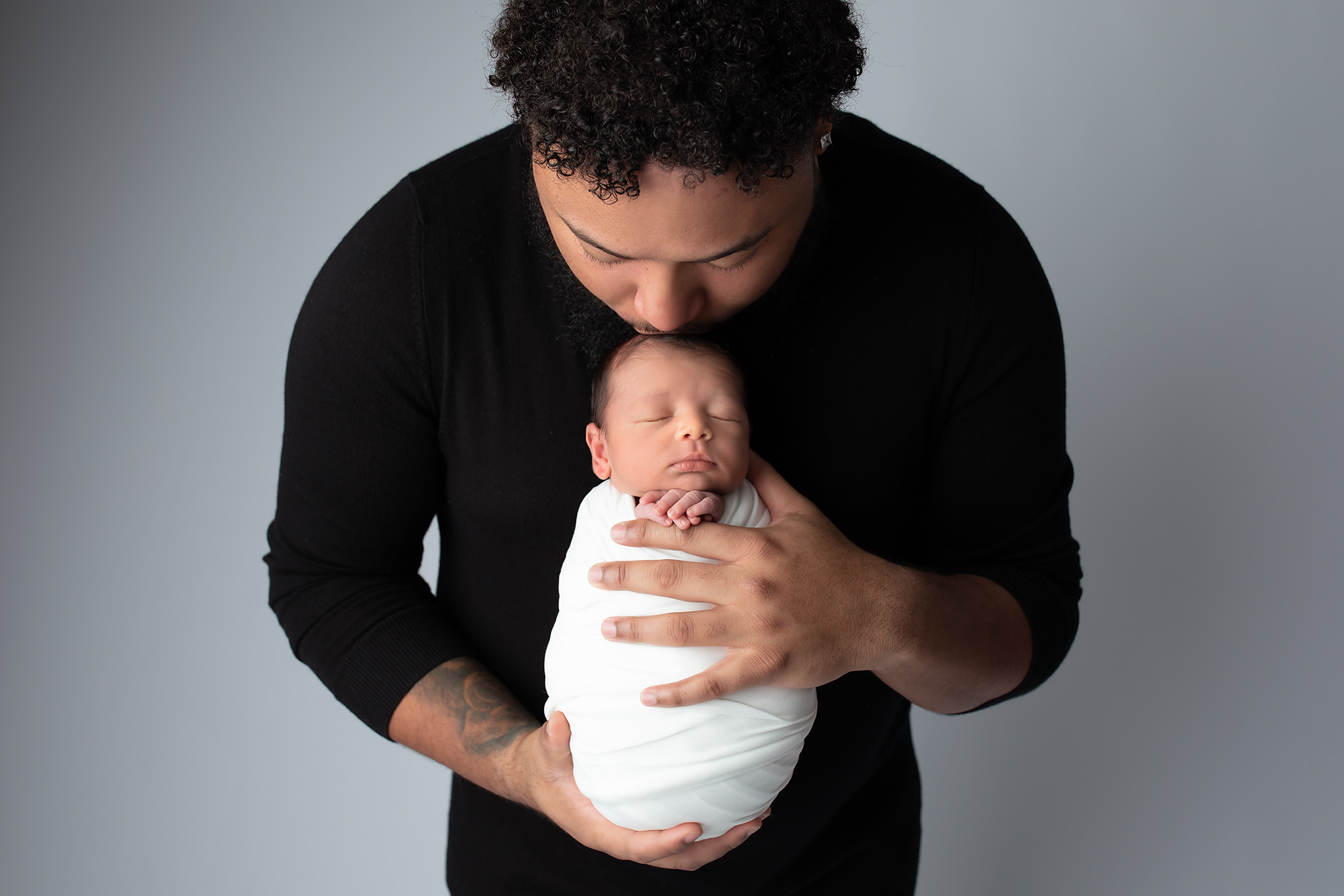 Dad kissing baby on the top of his head.